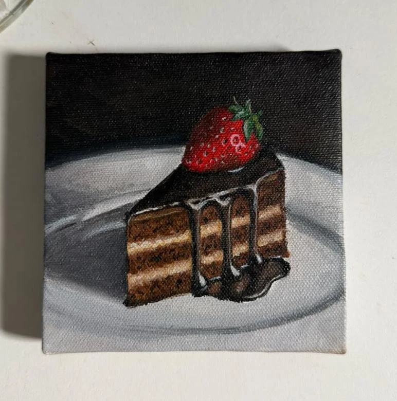 A strawberry-topped slice of chocolate cake makes a sweet little still life.