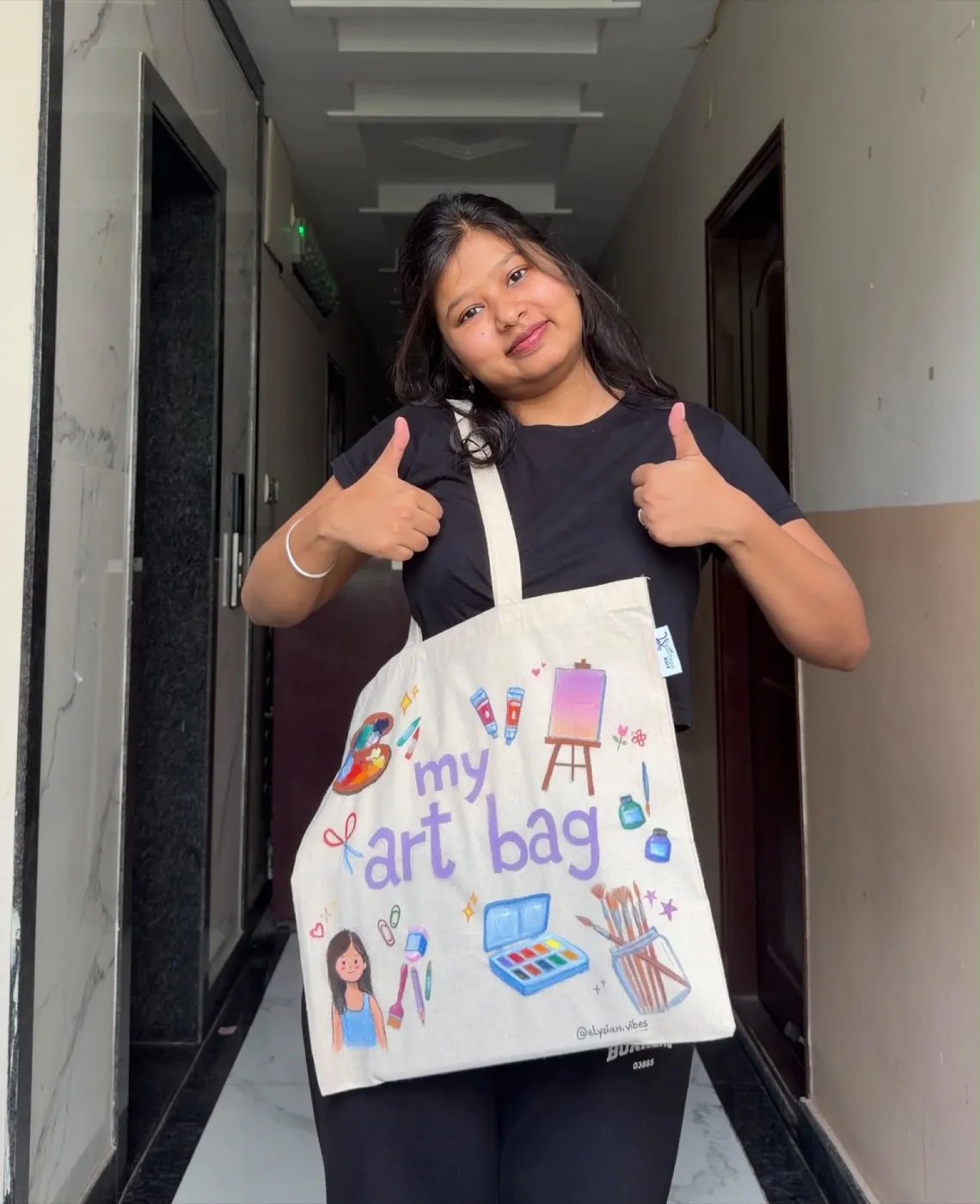 Isha holding her hand-painted art tote bag